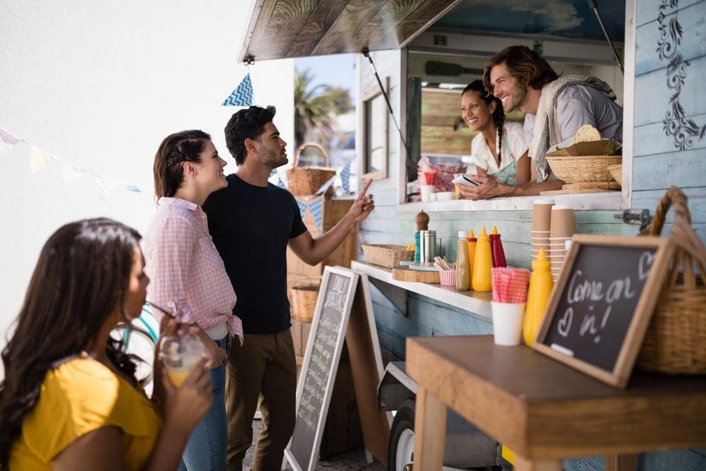 Smiling,Waiter,Taking,Order,From,Couple,At,Counter
